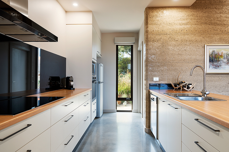 View down the kitchen with benches on both sides and a window at the end