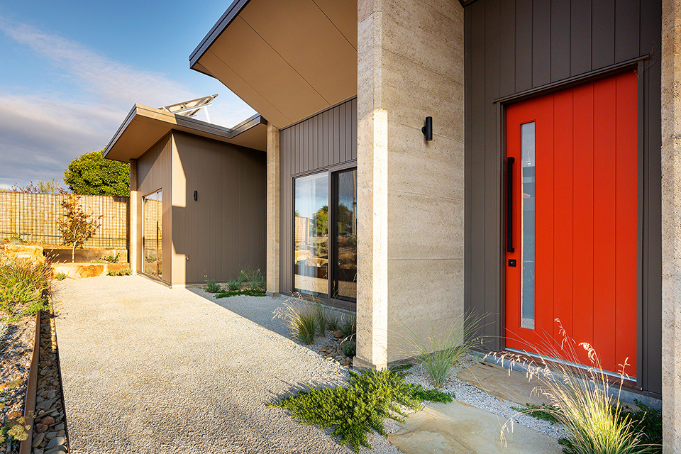 Side on view of exterior entry to the home, large red entry door