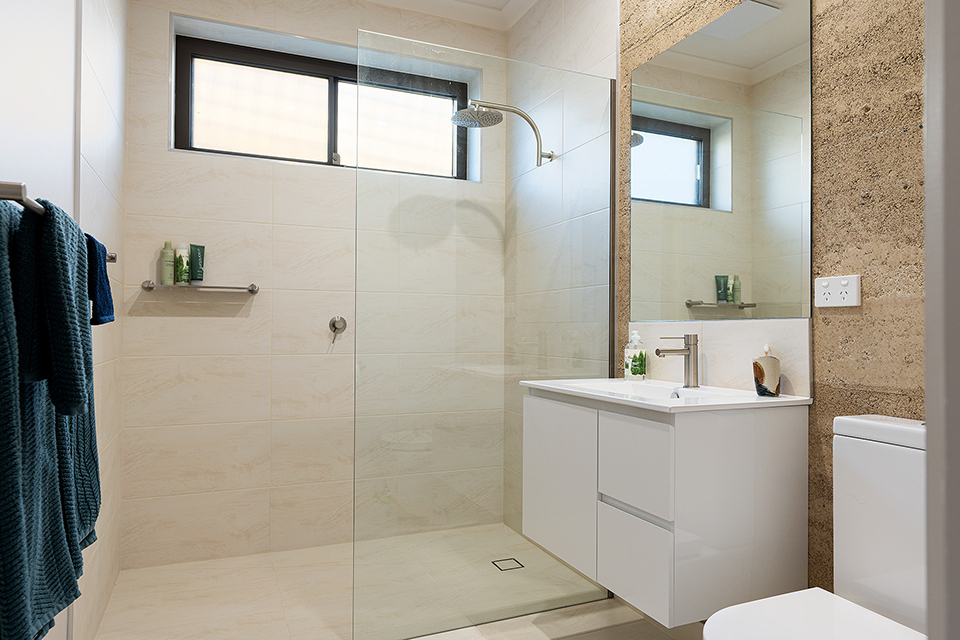 Bathroom with toilet, vanity and large shower with a blade screen